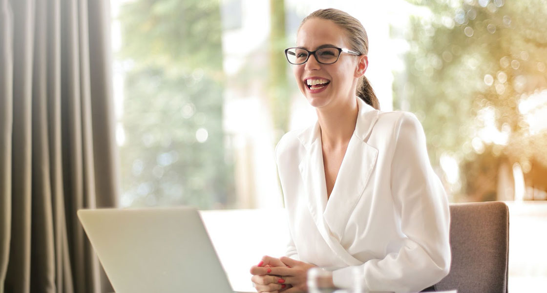 Woman smiling dressed in glasses and white corporate attire