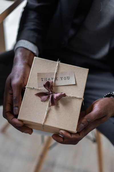 Man holding a gift box with ribbon and thank you card