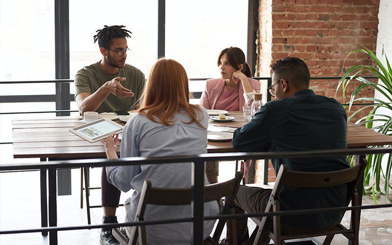 a team sitting around the table and communicating the use of systems in a company