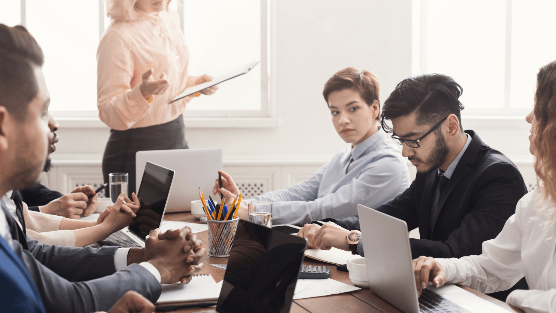 A diverse business team collaborates in front of a glass board covered in colorful sticky notes, mapping out actionable steps and priorities.