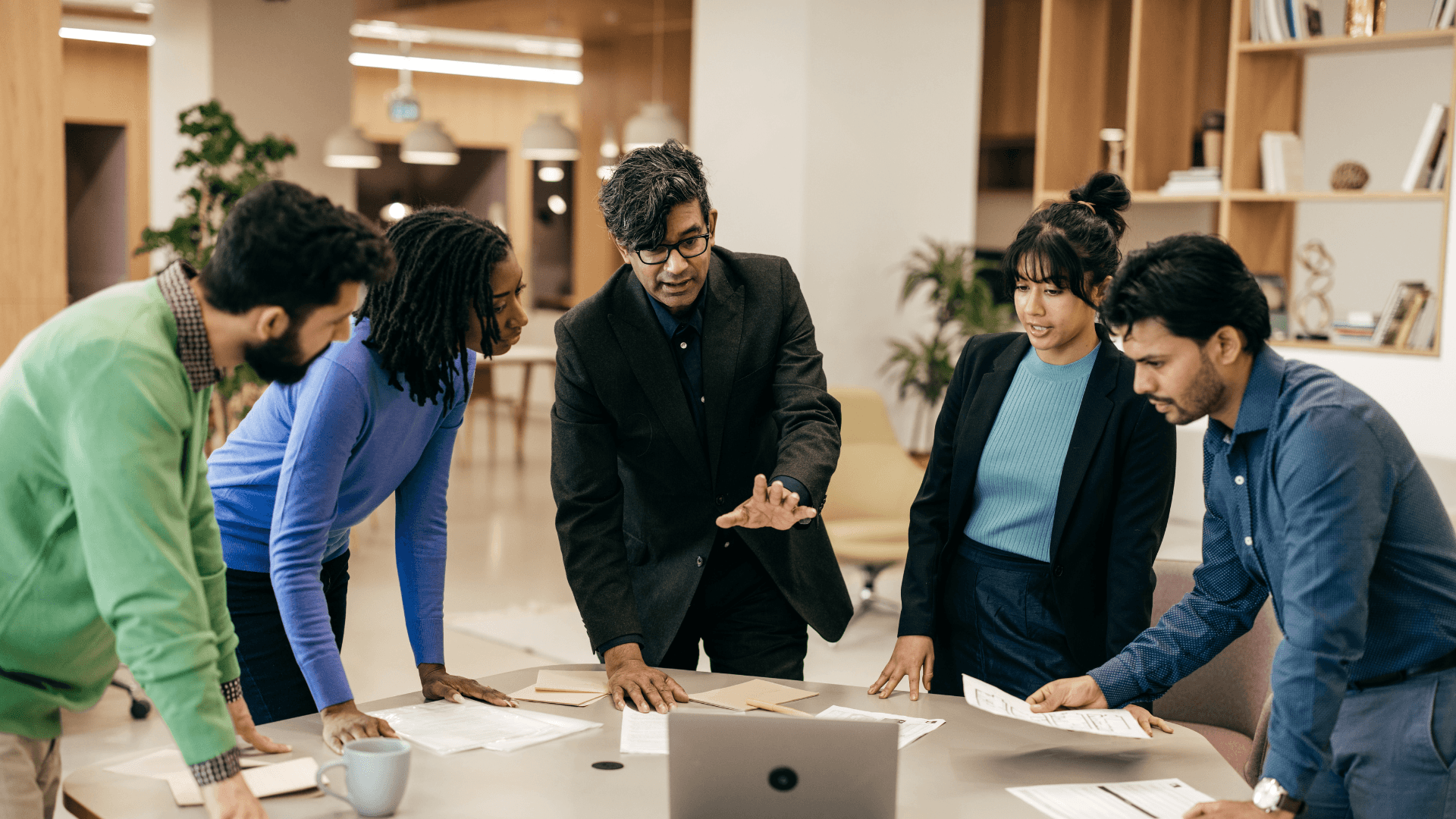 A team gathered in a modern office, actively strategising around a table, embodying the collaborative approach to growth and execution.