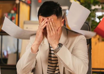 a man covering his face while sitting at a desk due to burnout and stress at work